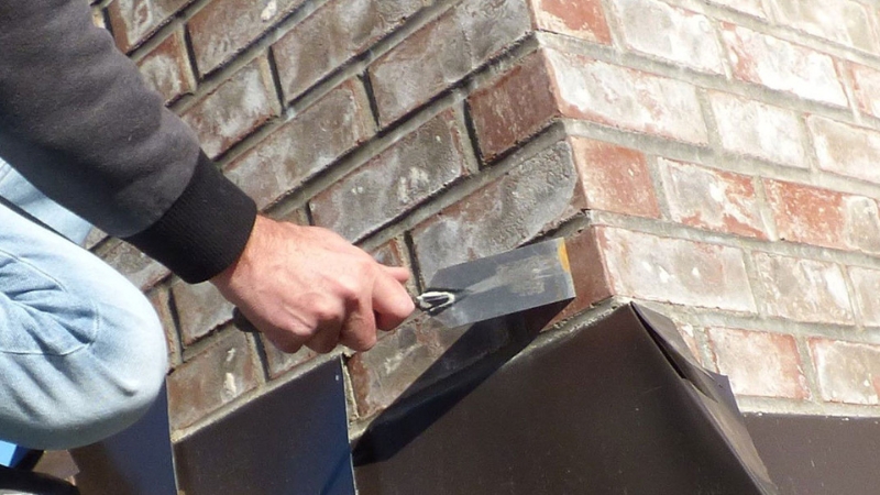 Man carrying out brick repointing on exterior house wall